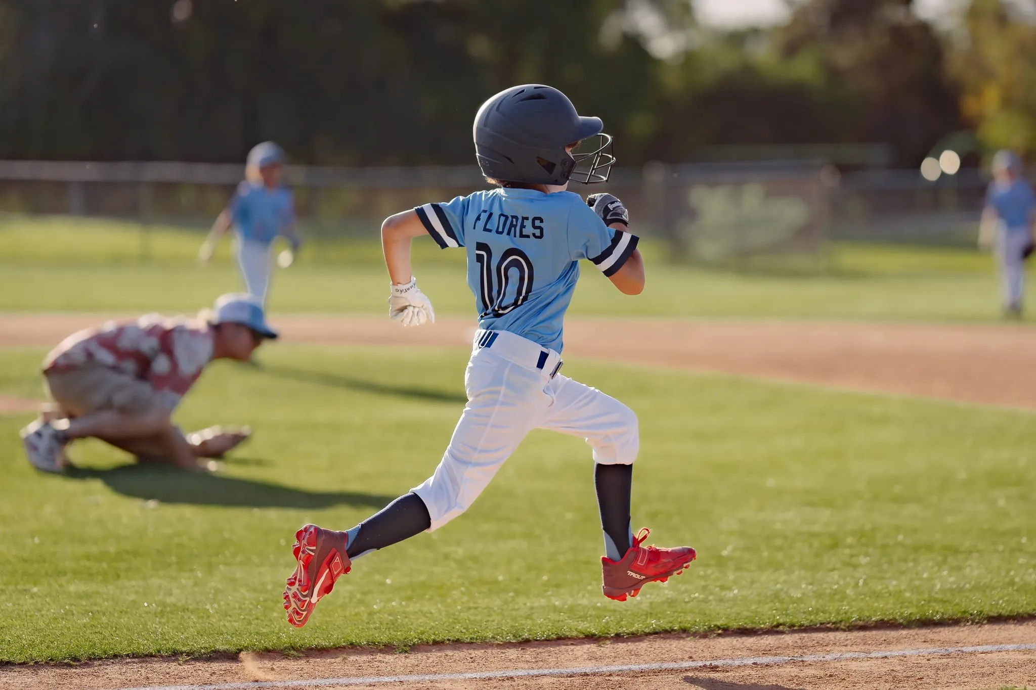 Batter sprints out of the box, airborne mid-stride, helmet flashing in evening sun