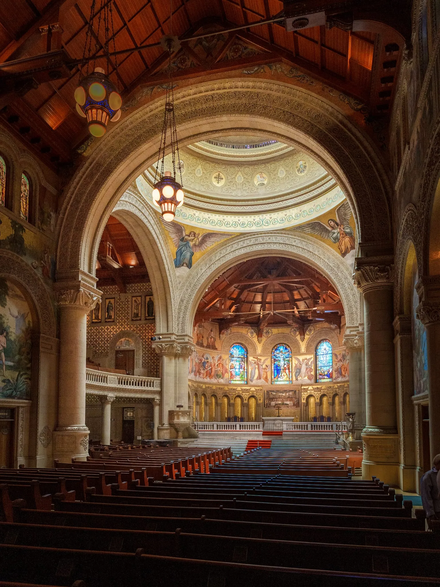 Side view through the arches of Stanford Memorial Church, stained glass and mosaics glowing over wooden pews