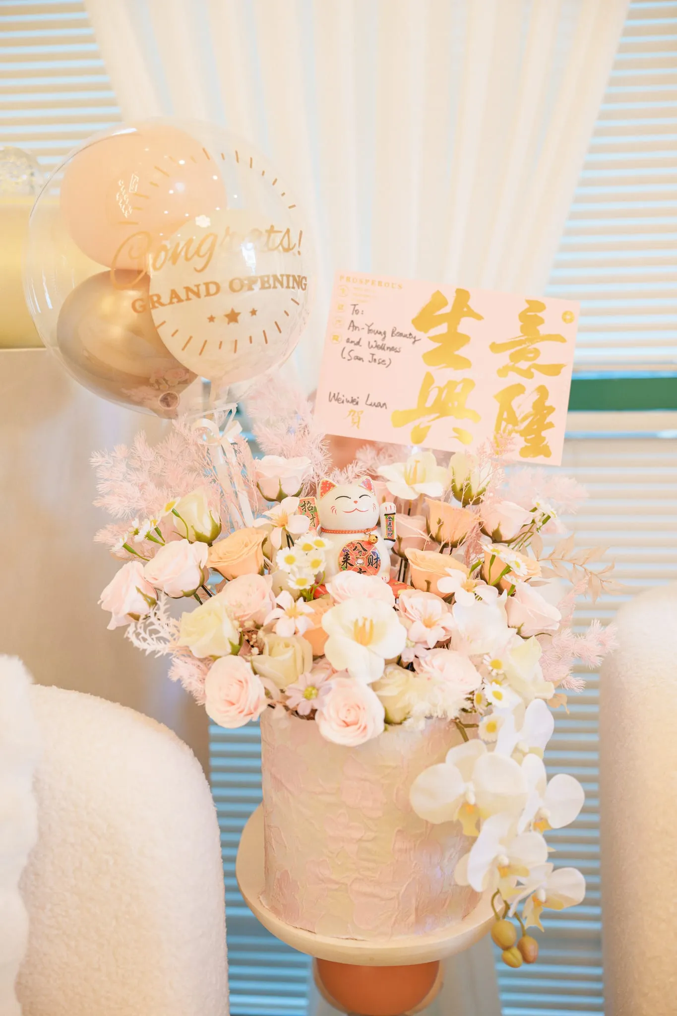 Grand-opening flower cake with blush roses, orchids, and congratulatory balloons at a San Jose studio launch