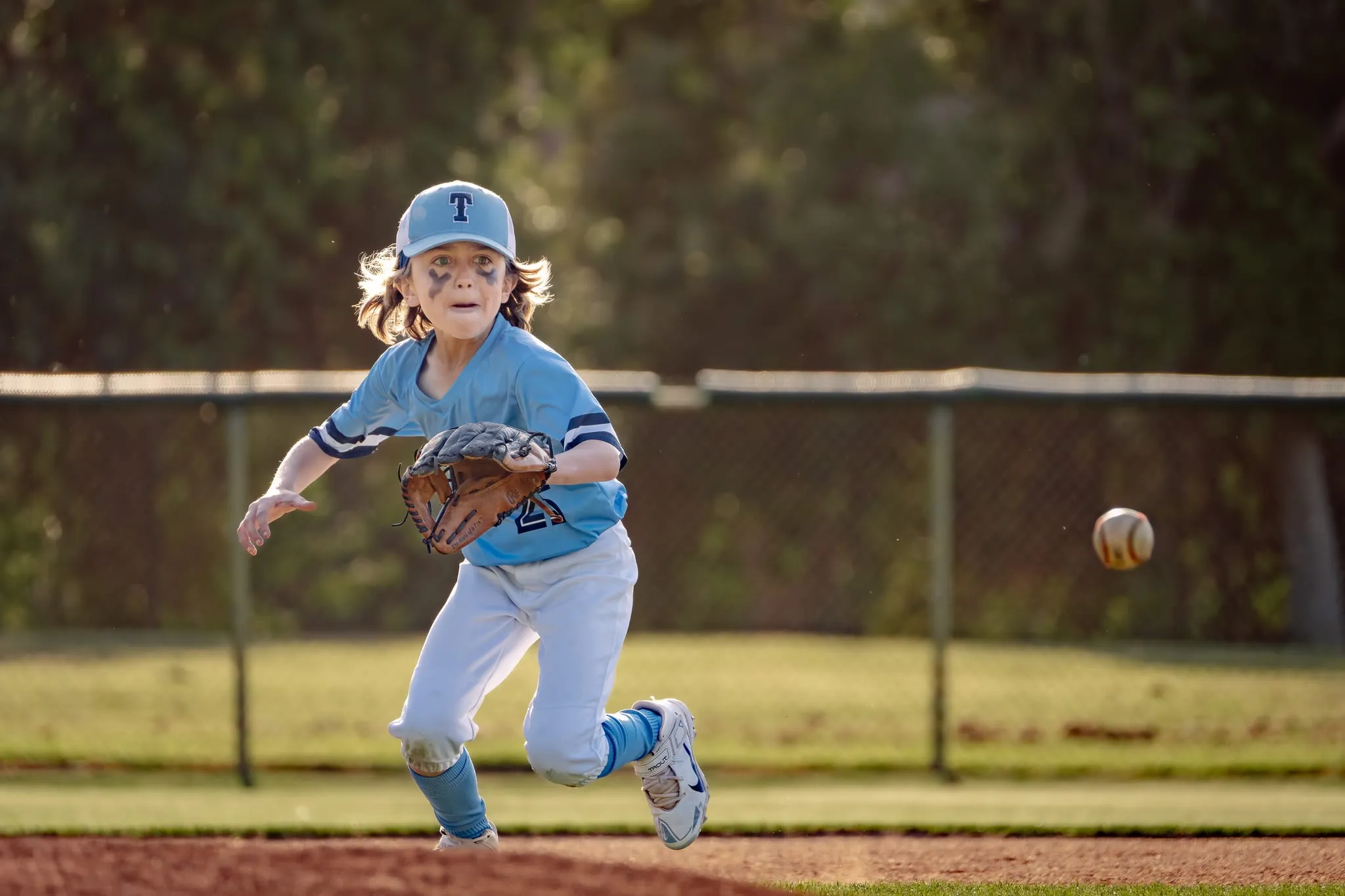 Fielder with eye black charges a bouncing ground ball, glove ready