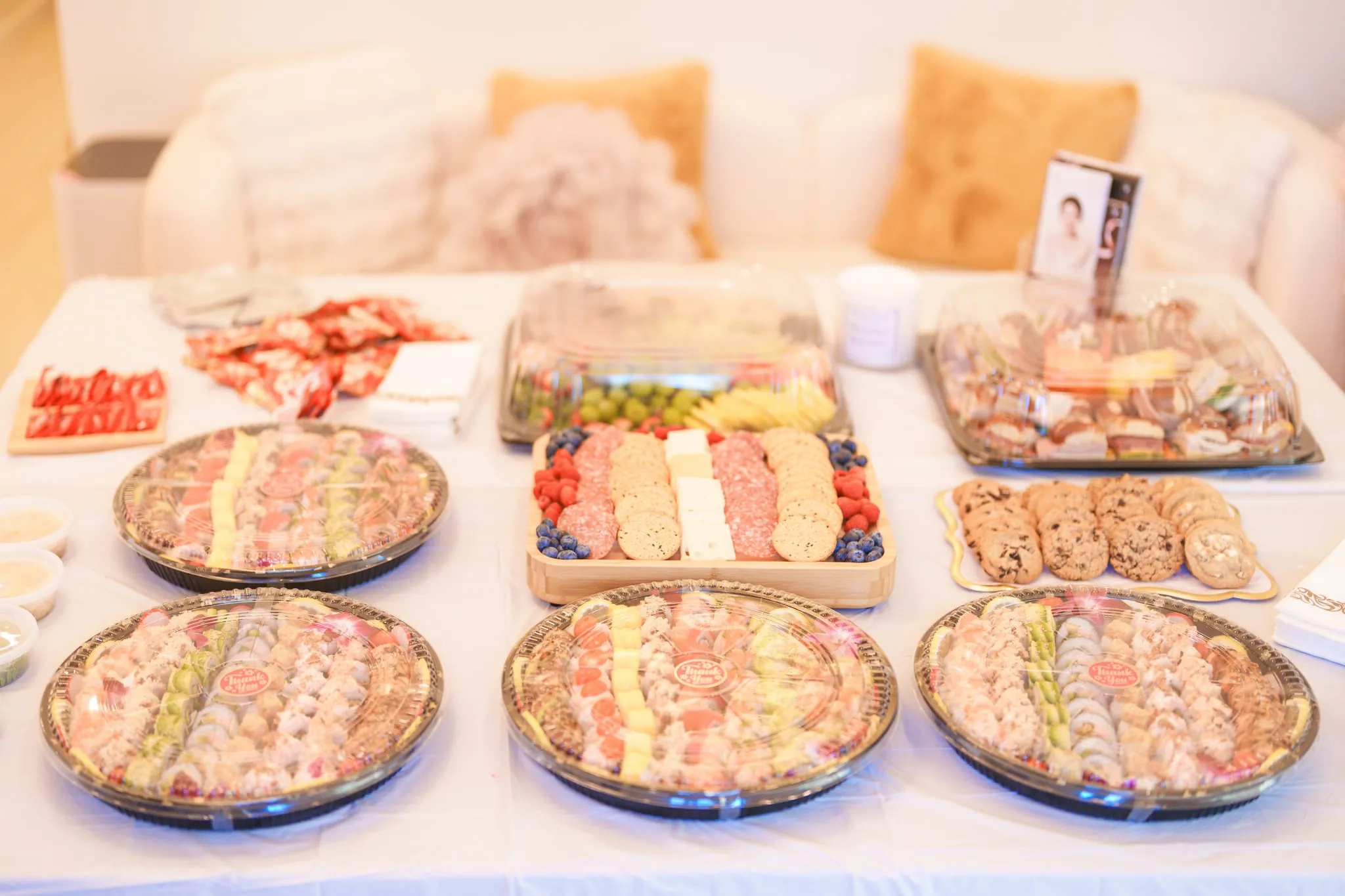 Catering trays of sushi, charcuterie, and desserts arranged for a boutique's opening reception in San Jose