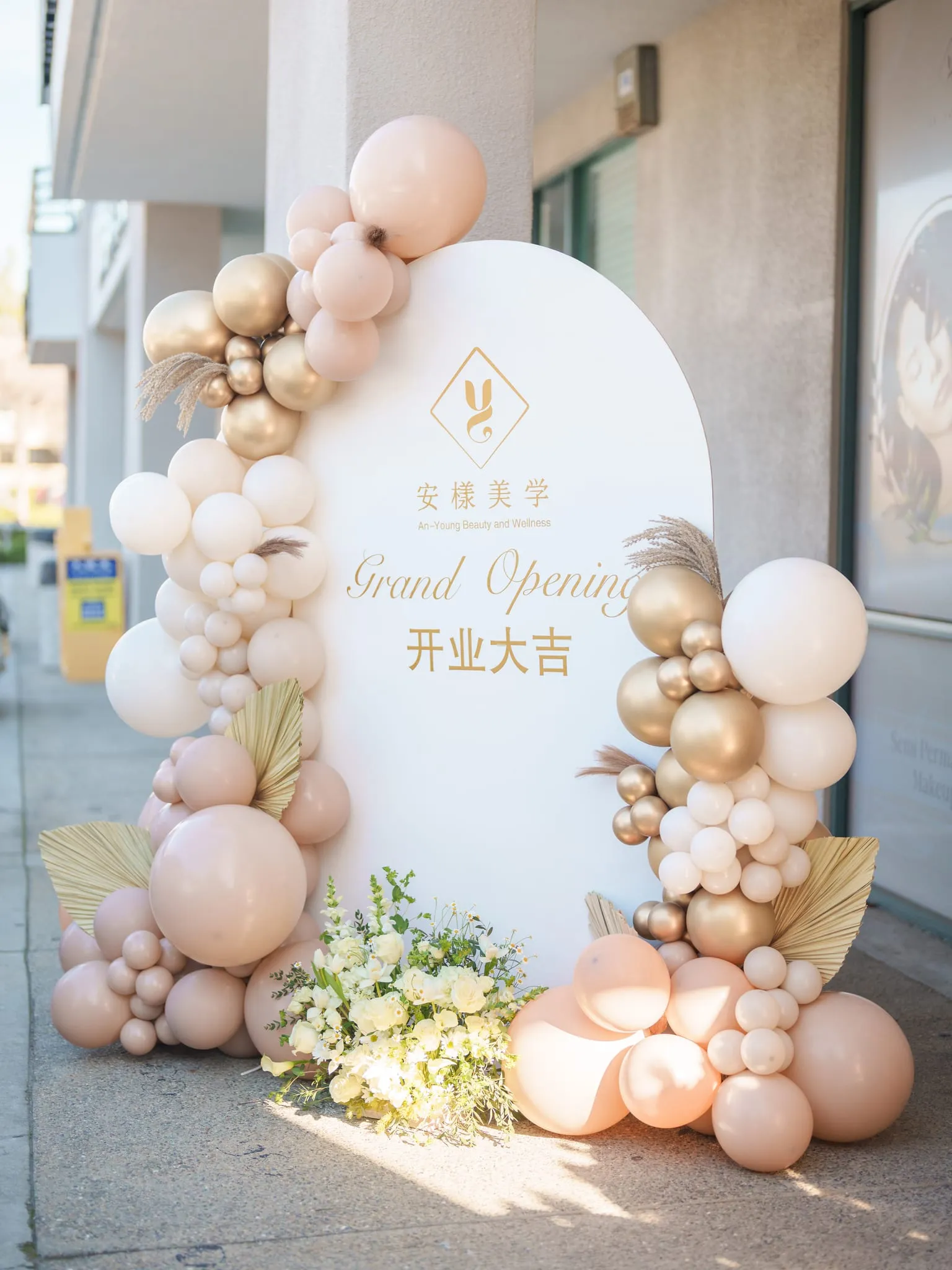 Balloon arch in blush and gold frames a grand-opening sign outside a San Jose beauty studio storefront